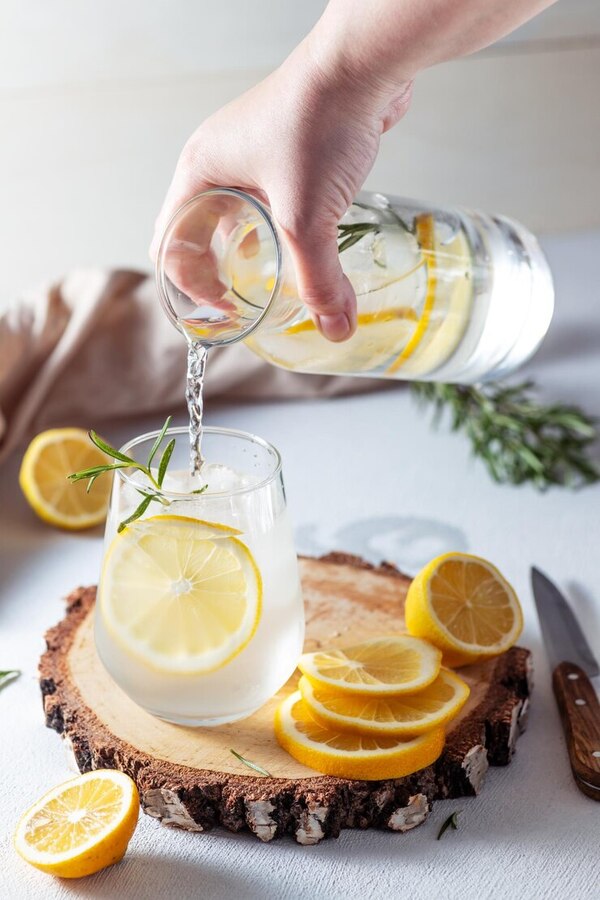 Víz, citromszeletek és friss gyümölcsök az asztalon, pihenőre hívó elrendezésben